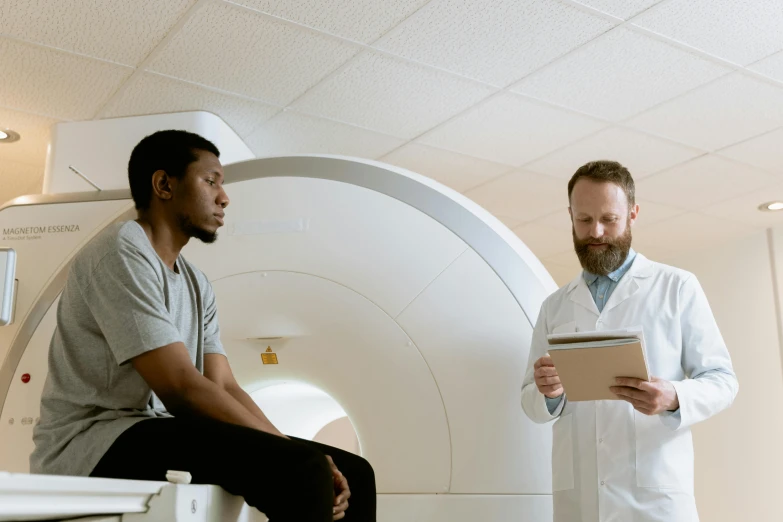 a couple of men standing next to each other in a room, mri, brown, man sitting facing away, diverse