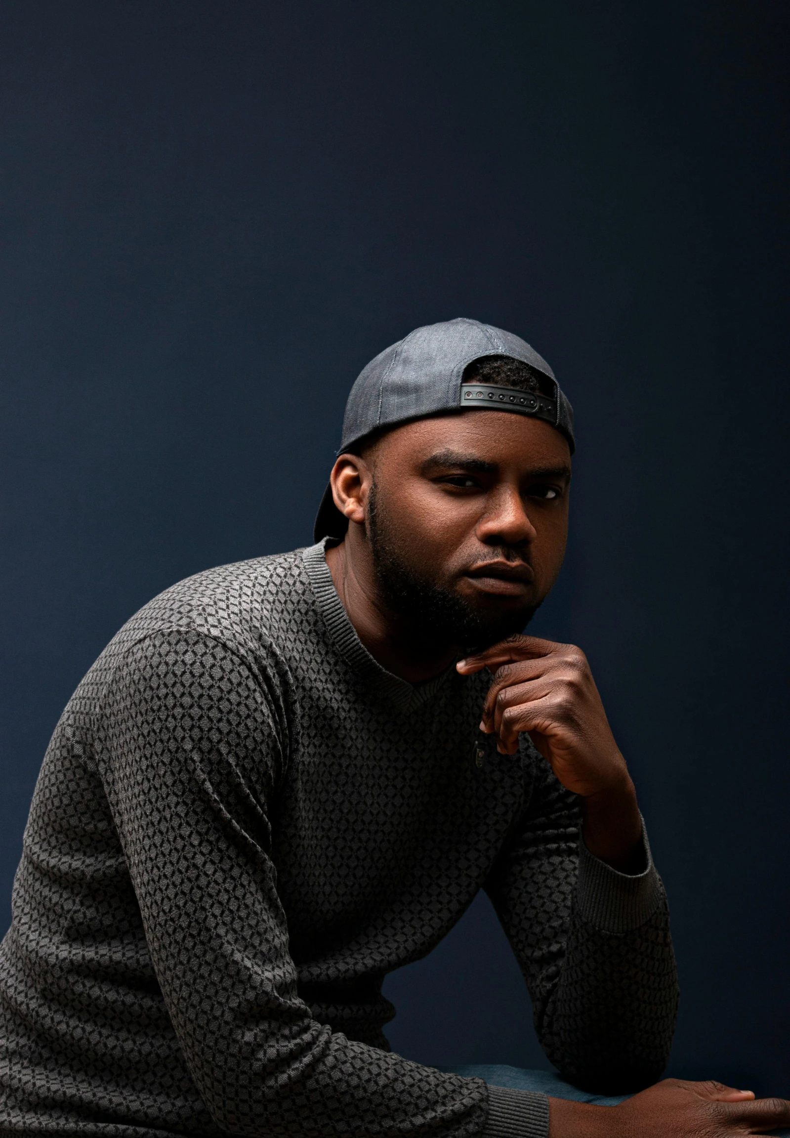 a man sitting in front of a laptop computer, an album cover, inspired by Paul Georges, trending on unsplash, hurufiyya, standing with a black background, jaylen brown, headshot portrait, gray men