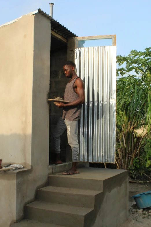 a man standing in the doorway of a building, offering a plate of food, godwin akpan, tall thin build, at home