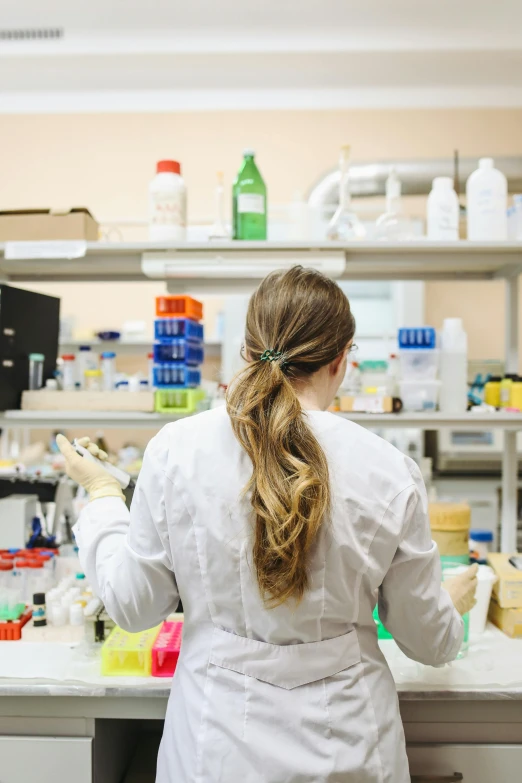 a woman in a lab coat working in a laboratory, by Anna Haifisch, long shot from the back, college, trending, featured