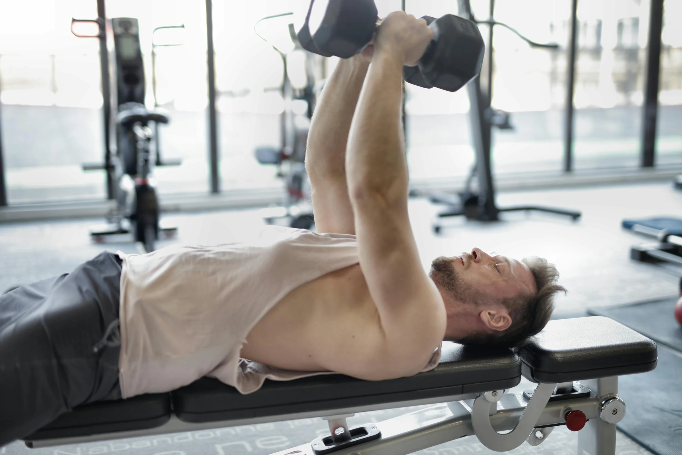 a man laying on a bench with a pair of dumbbells, private press, profile image, manly, local gym, soft natural light