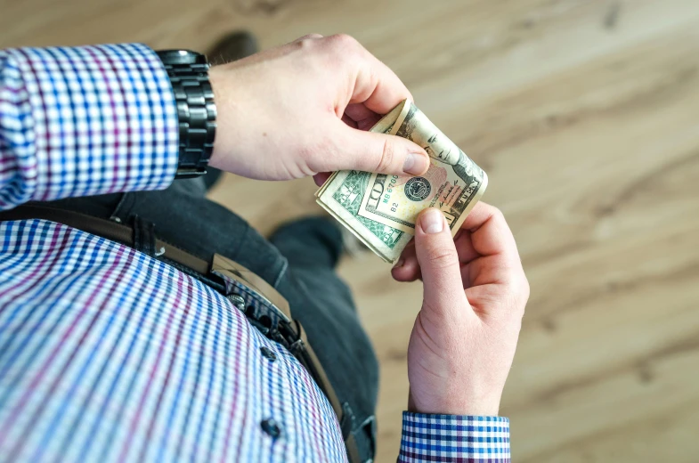 a man holding a bundle of money in his hand, pexels contest winner, folds of belly flab, wearing business casual dress, wearing a shirt and a jean, pixelated