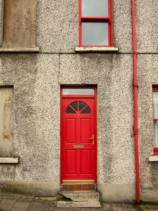 a red door that is on the side of a building, an album cover, by Kevin Connor, pexels contest winner, stonework, houses, exterior photo, thumbnail