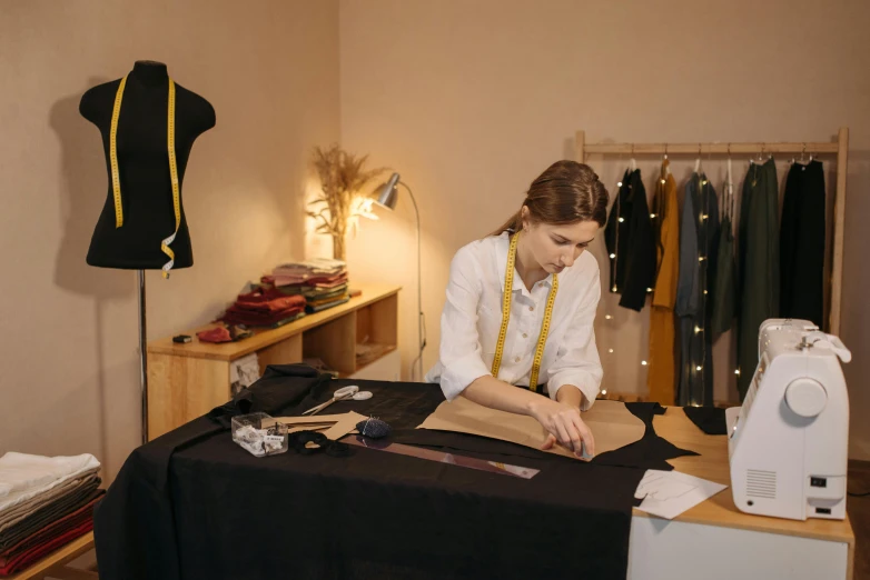 a woman sitting at a table in front of a sewing machine