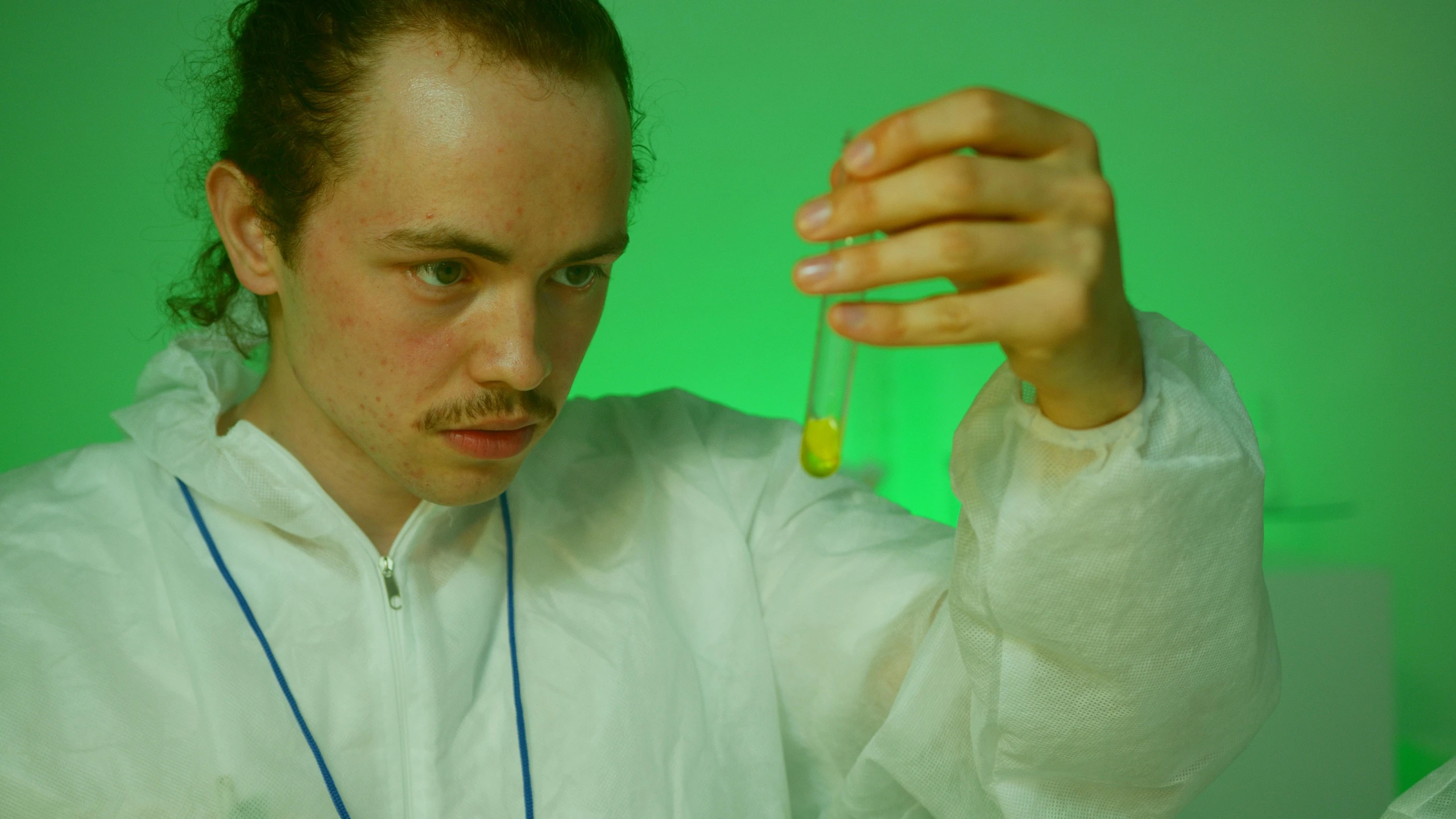 a man in a lab coat holding a test tube, an album cover, by Attila Meszlenyi, green saliva, concentrated, chemical woekshop, frank dillane
