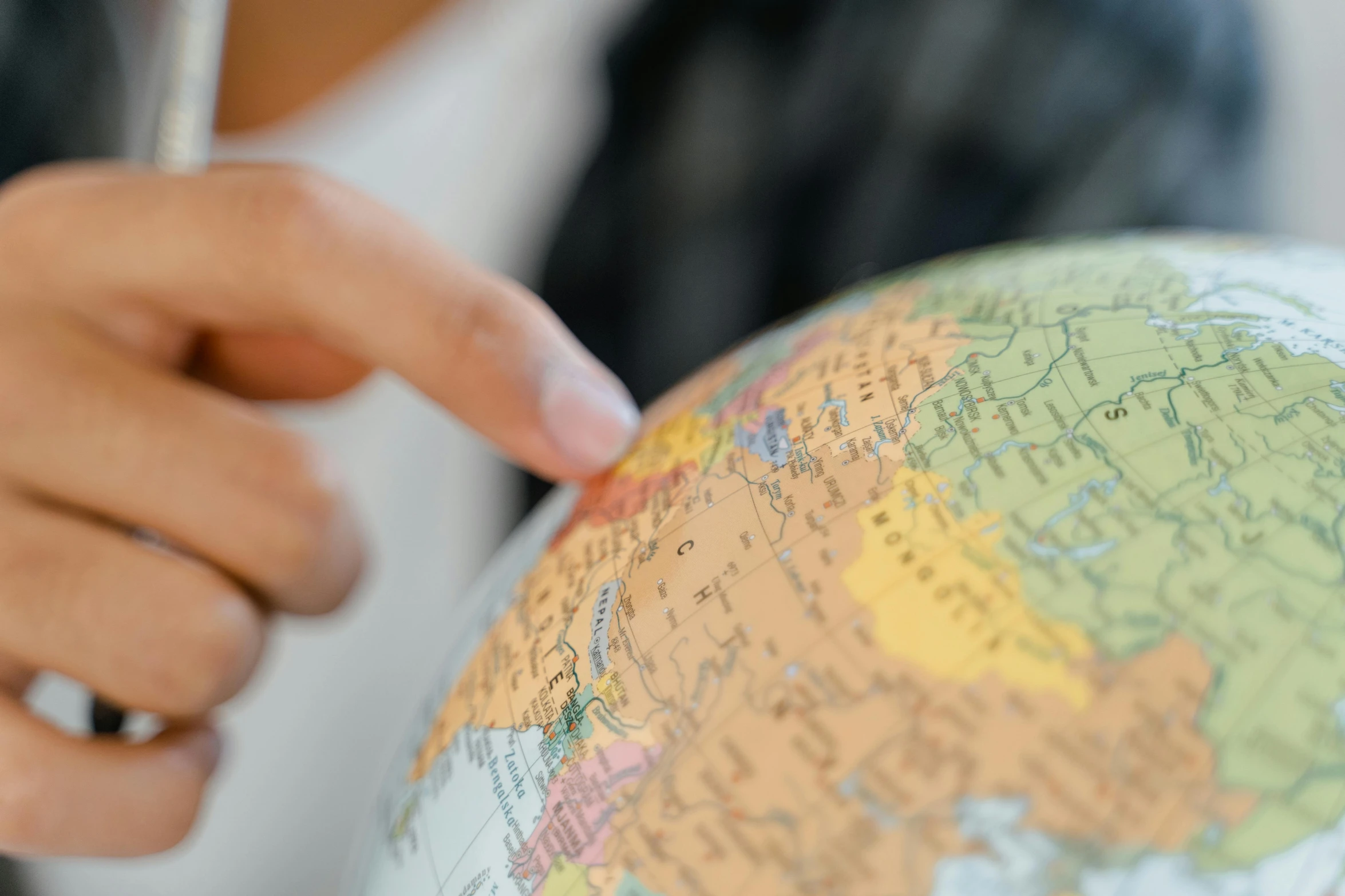 a close up of a person holding a pen over a globe, photograph taken in 2 0 2 0, schools, pointing, traveller