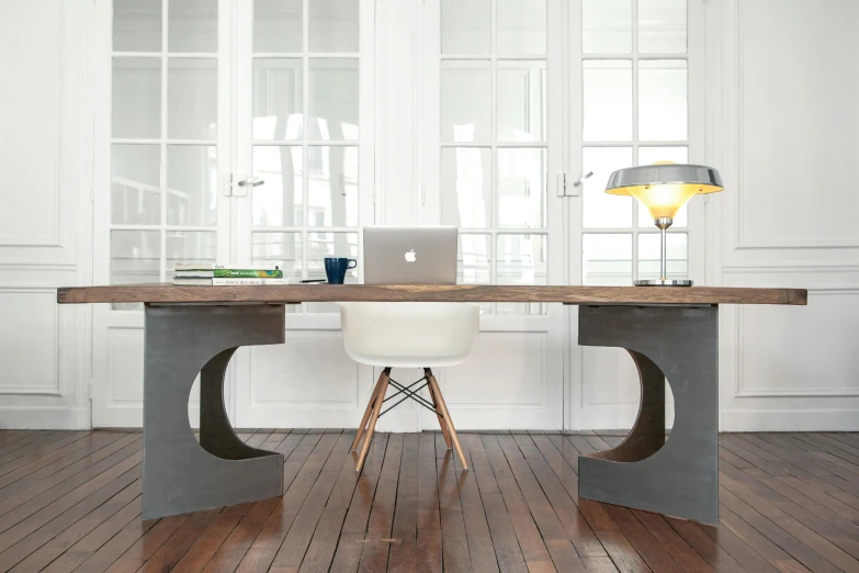 a laptop computer sitting on top of a wooden desk, inspired by Afewerk Tekle, concrete art, dining table, steel archways, large shot, grey