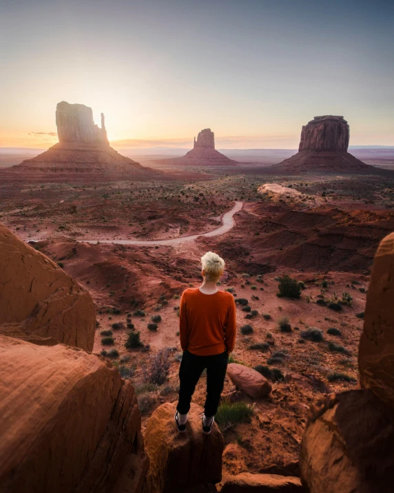 a man standing on top of a rock in the desert, by Scott Gustafson, unsplash contest winner, temples behind her, lgbtq, style of monument valley, 5 0 0 px