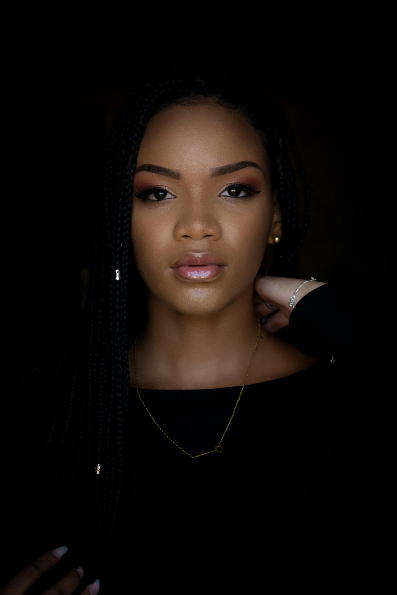 a woman in a black top posing for a picture, black hair in braids, softly lit, profile image, ( ( dark skin ) )