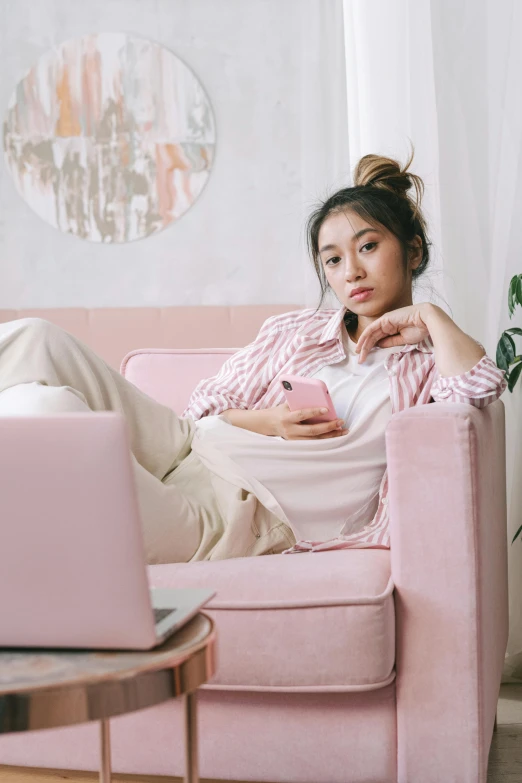 a woman sitting on a pink couch with a laptop, inspired by Ruth Jên, trending on pexels, aestheticism, disappointed, young asian woman, wearing pajamas, instagram picture