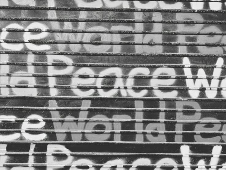 a black and white photo of graffiti on the side of a building, pexels, graffiti, world peace, header text”, inner peace, on a mini world