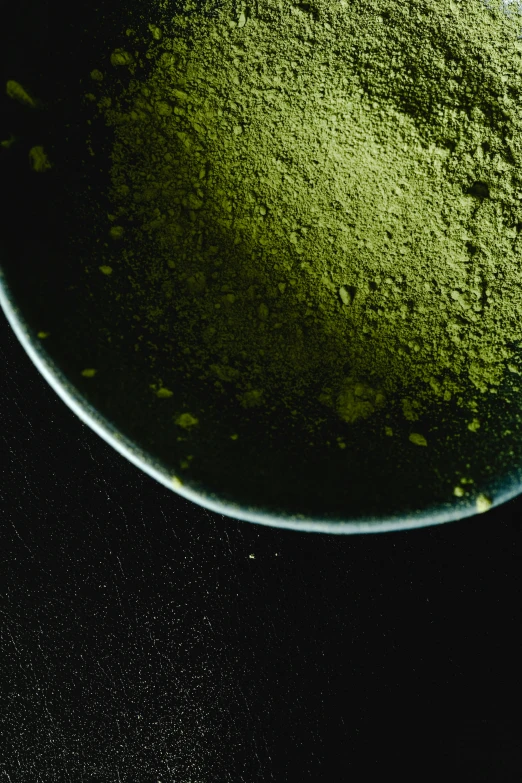 a bowl filled with green powder sitting on top of a table, a microscopic photo, inspired by Gatōken Shunshi, renaissance, seen from space, green tea, up close, round-cropped