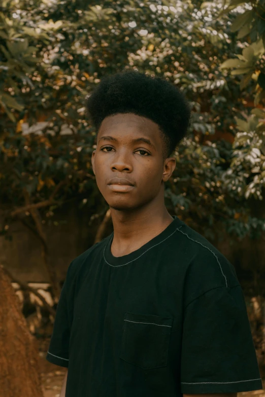 a young man standing in front of a tree, by Maxwell Bates, trending on pexels, realism, black teenage boy, halfbody headshot, serious look, high quality photo