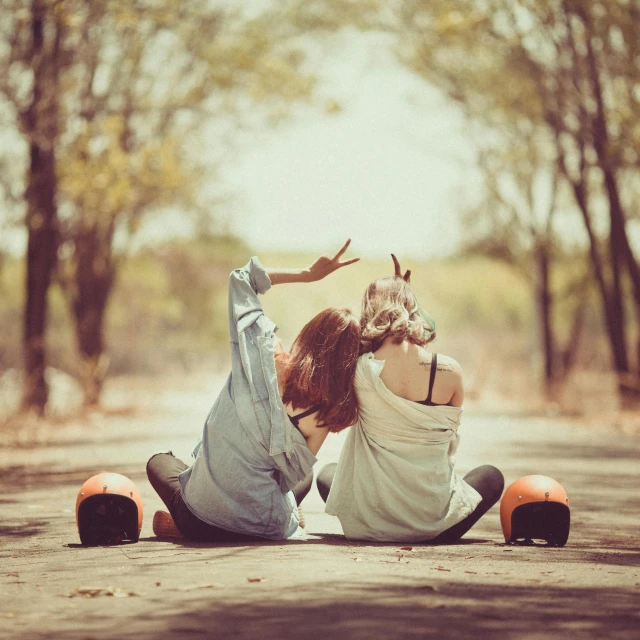 a woman laying on top of a skateboard on a road, a picture, by Lucia Peka, shutterstock, romanticism, two girls, color vintage, good friends, ((((dirt brick road))))