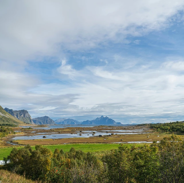 a large body of water sitting on top of a lush green field, by Roar Kjernstad, hurufiyya, mountain in the background, dessert, autumn, multiple stories