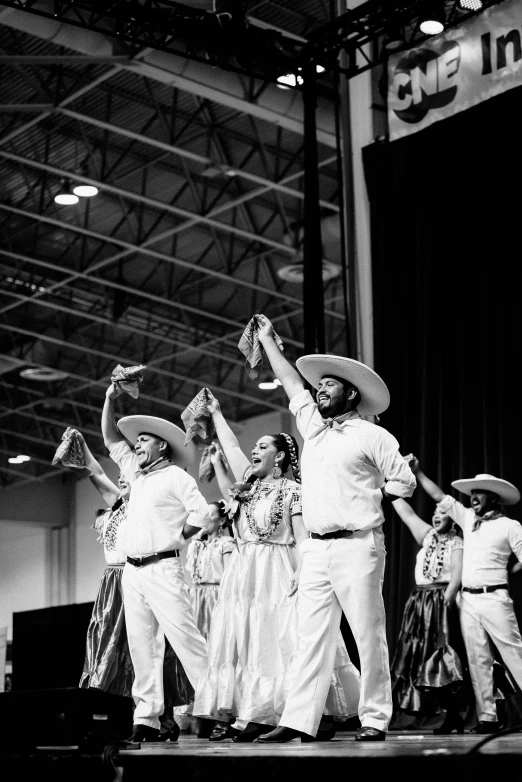 a group of men standing on top of a stage, a black and white photo, by Byron Galvez, happening, folklorico, instagram post, the texas revolution, expo-sure 1/800 sec at f/8