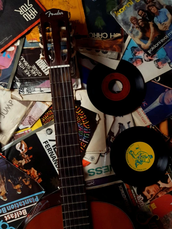 a guitar sitting on top of a pile of records, an album cover, inspired by William Harnett, trending on pexels, 1968 cut out collage, ( ( theatrical ) ), in detail, the back rooms