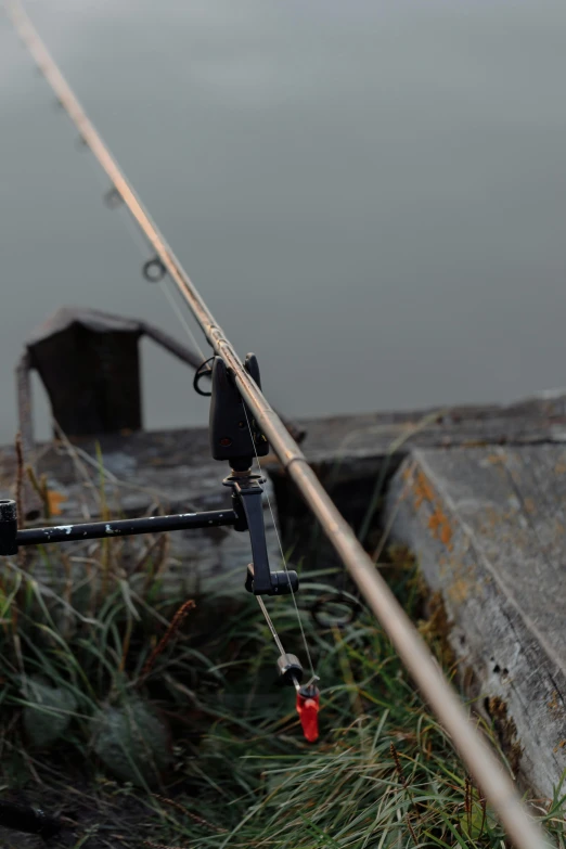 a close up of a fishing pole near a body of water, by Jan Tengnagel, b - roll, various posed, menacing, tripod