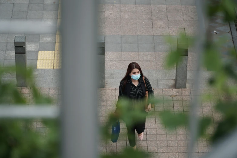 a woman wearing a face mask walking down a sidewalk, a picture, looking down from above, square, qiangshu, high quality image