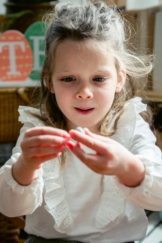 a little girl holding something in her hands, process art, tactile buttons and lights, offering the viewer a pill, carefully crafted, schools