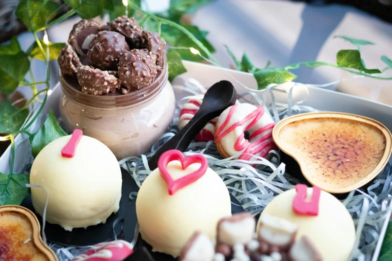 a tray of desserts sitting on top of a table, by Lee Loughridge, unsplash, hurufiyya, pink, chocolate, manuka, holiday vibe