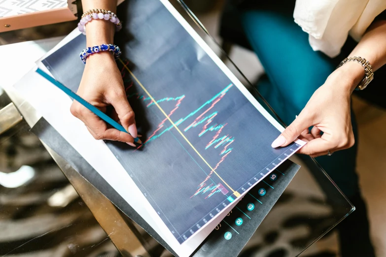 a woman sitting at a table writing on a piece of paper, trending on pexels, analytical art, waveforms on top of square chart, handcrafted, thumbnail, markets