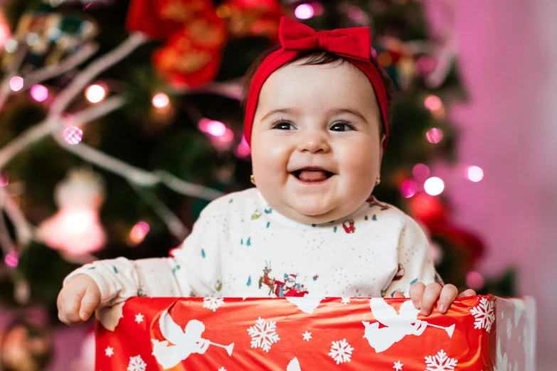 a baby holding a christmas present in front of a christmas tree, a portrait, by Julia Pishtar, pexels contest winner, happening, happily smiling at the camera, avatar image, close up portrait photo, thumbnail