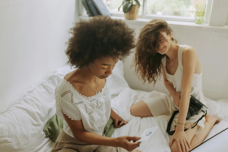 a couple of women sitting on top of a bed, pexels contest winner, varying ethnicities, playing games, instagram post, hair