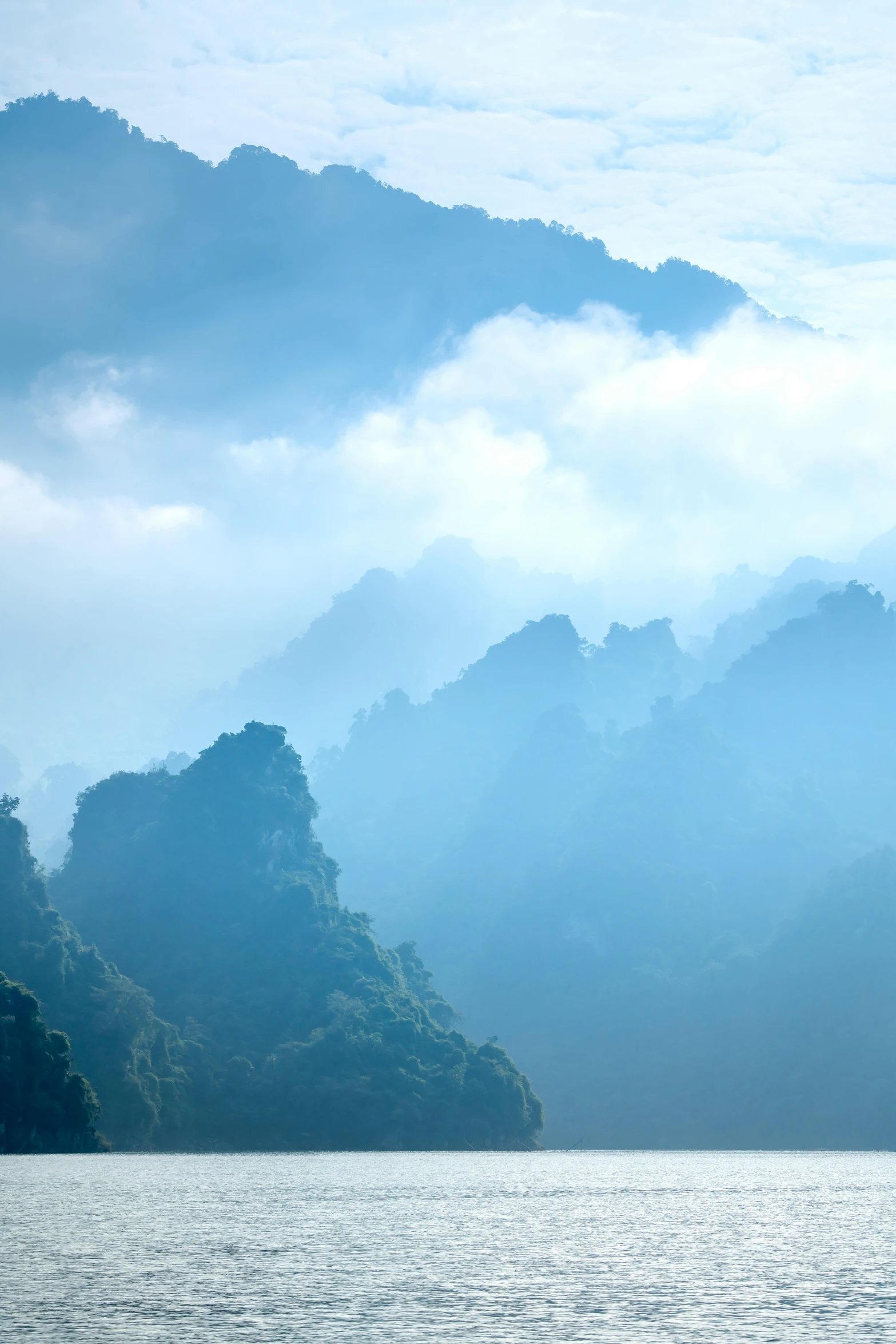 a boat floating on top of a large body of water, an album cover, inspired by Li Keran, trending on unsplash, romanticism, mist in valley, guangjian, shades of blue, paul barson