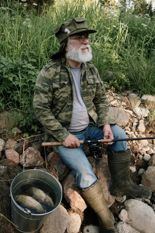 a man sitting on a pile of rocks holding a fishing rod, overalls and a white beard, camo, 2019 trending photo, 2 5 6 x 2 5 6 pixels