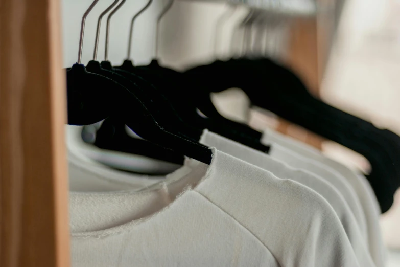 a row of clothes hanging on a clothes rack, unsplash, private press, dressed in a white t shirt, wearing a black t-shirt, zoomed in, taken in the late 2010s