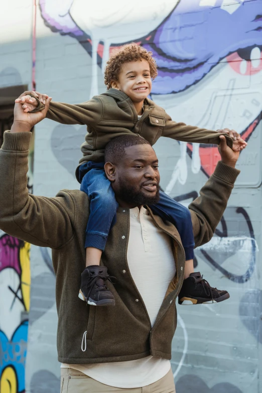 a man carrying a little boy on his shoulders, pexels contest winner, kevin hart, movie still, gen z, richly colored