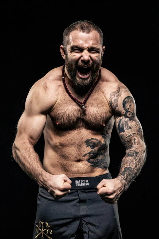 a shirtless man standing in front of a black background, a tattoo, inspired by Brian 'Chippy' Dugan, hasbulla magomedov, manically laughing, rugged beard, strong fighter in leathers