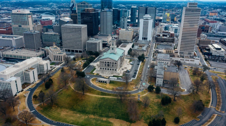 an aerial view of a city with tall buildings, by Dan Frazier, unsplash contest winner, visual art, tn, on a great neoclassical square, official courthouse, grass field surrounding the city