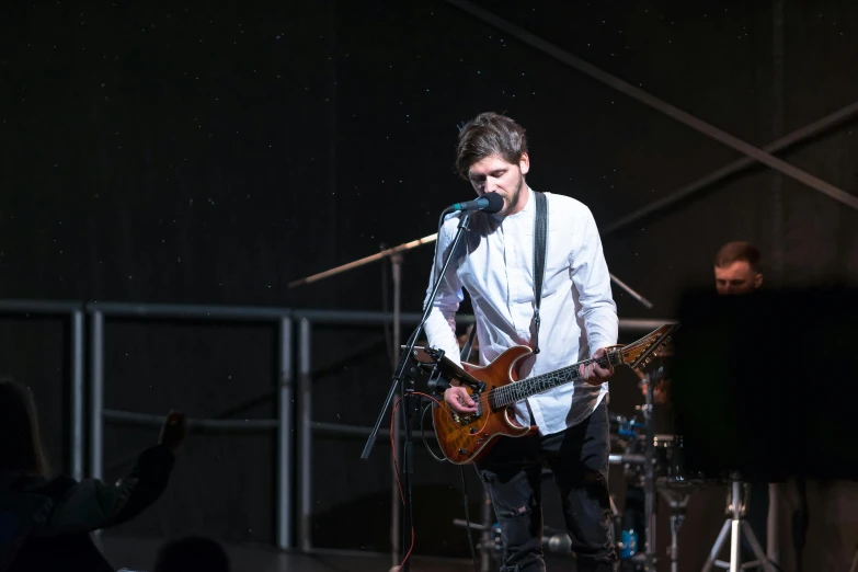 a man that is playing a guitar on a stage, spoon, raphael personnaz, white sky, promo image
