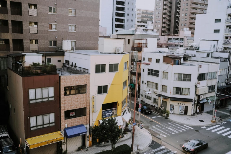 a city street filled with lots of tall buildings, a picture, unsplash, shin hanga, yellow awning, japanese high school, standing on a rooftop, 2000s photo