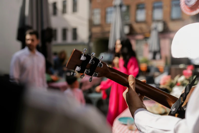 a man that is playing a guitar in the street, an album cover, by Ejnar Nielsen, pexels contest winner, hurufiyya, midsommar color theme, audience in the background, performance, holiday season