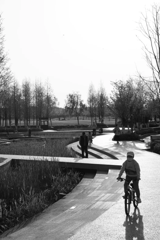 a black and white photo of a person riding a bike, inspired by Zhao Yong, walking at the garden, waterway, urban playground, open landscape