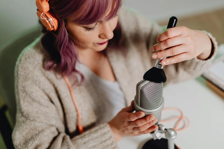 a woman sitting at a table in front of a microphone, trending on pexels, crafting, furry artist, wearing purple headphones, avatar image