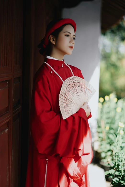 a woman in a red dress holding a fan, a portrait, inspired by Gu An, pexels contest winner, wearing an academic gown, bao phan, red hat, vintage aesthetic