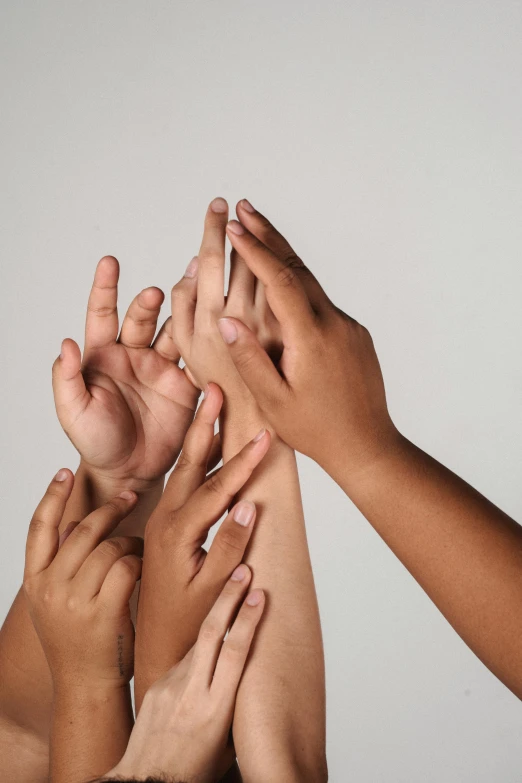 a group of people with their hands in the air, by Gavin Hamilton, skincare, on grey background, synthetic skin, finger