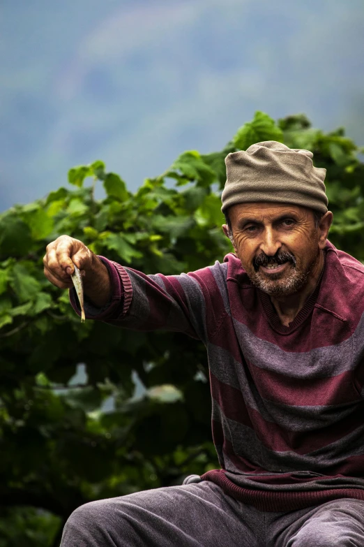 a man sitting on top of a wooden bench, by Ibrahim Kodra, pexels contest winner, renaissance, farming, vine covered, pointing at the camera, oldman with mustach