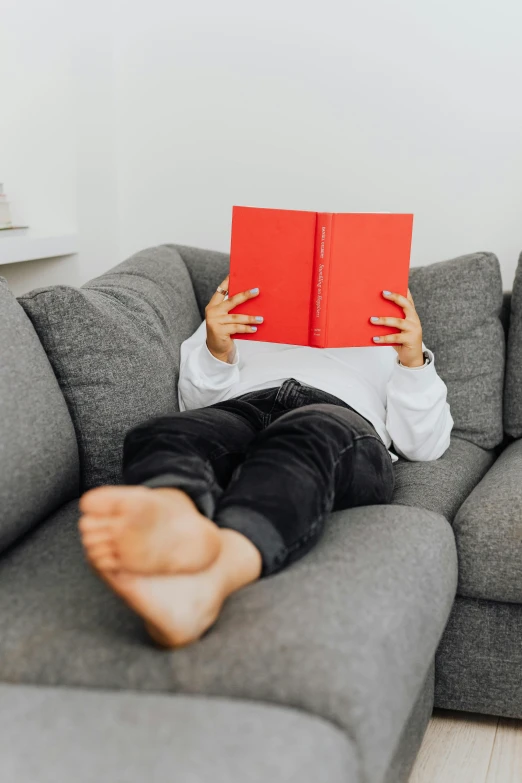 a person laying on a couch reading a book, red and grey only, kid, connectivity, full-body