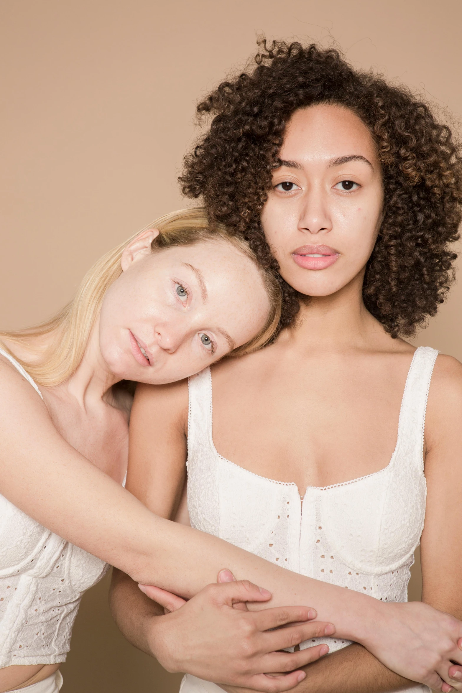 a couple of women standing next to each other, inspired by Vanessa Beecroft, trending on pexels, renaissance, brown eyes and white skin, lesbian embrace, mixed race, on simple background