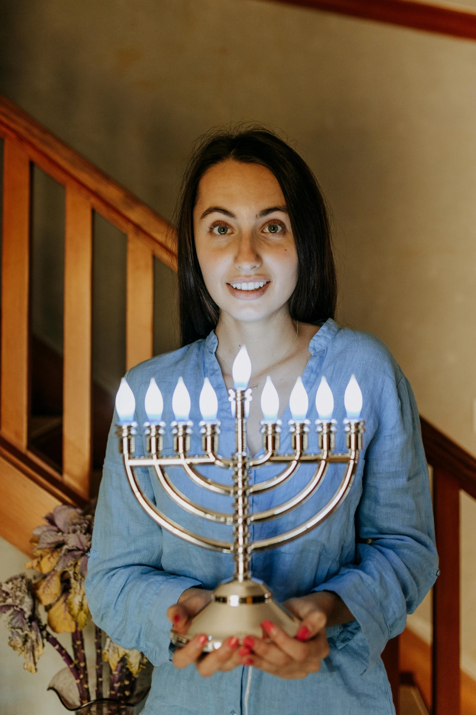 a woman holding a menorah in her hands, slightly smiling, square, jen atkin, 30 years old woman