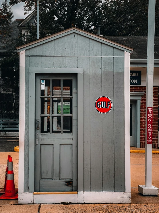 a small gray building sitting on the side of a road, by Carey Morris, pexels contest winner, old signs, 1/6 garage resin kit, gulf, 🚿🗝📝