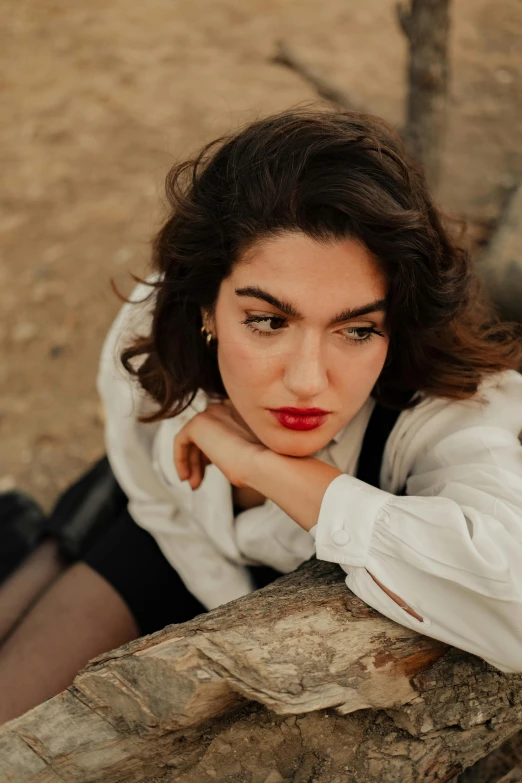 a woman sitting on top of a wooden log, inspired by Elsa Bleda, trending on pexels, renaissance, androgynous face, young middle eastern woman, red lipstick, dua lipa