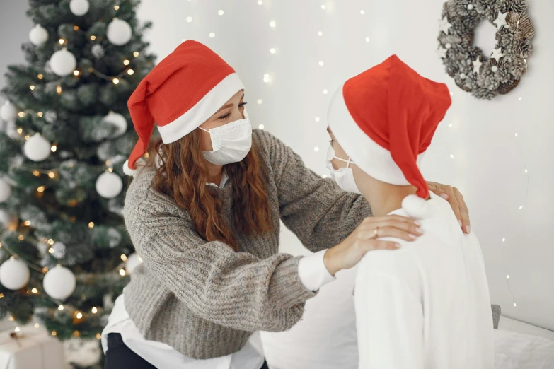 a woman putting a face mask on another woman, by Julia Pishtar, pexels, fine art, wearing santa hat, hugs, avatar image, grey