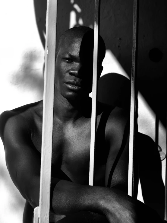 a black and white photo of a man holding a surfboard, inspired by Gordon Parks, figuration libre, behind bars, adut akech, supermodel, 1990 photograph