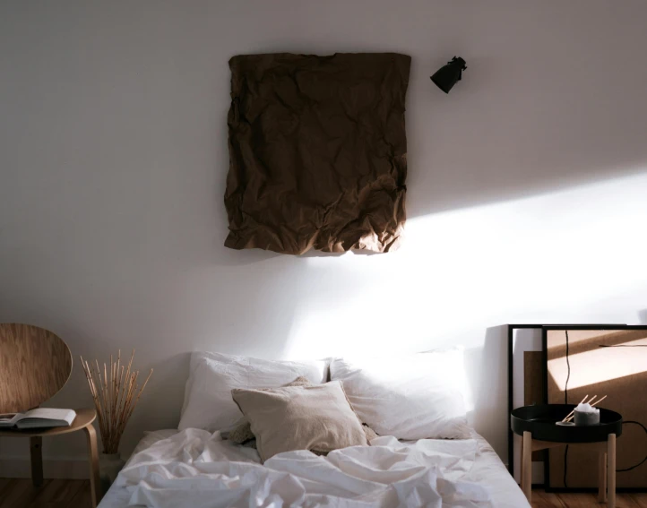 a bed room with a neatly made bed and a chair, inspired by Elsa Bleda, pexels contest winner, minimalism, gradient brown to white, low sun, white sheets, wall art